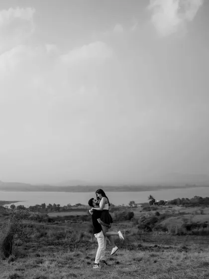 A wide shot that captures the feeling of freedom and joy. This black and white photo from a pre-wedding shoot shows the couple against a vast landscape, symbolizing the grand adventure they are about to embark on.