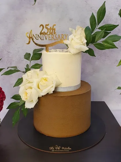 A closer look at the silver jubilee anniversary cake, showing the contrast between the smooth chocolate bottom tier and the white top tier, decorated with elegant white roses.