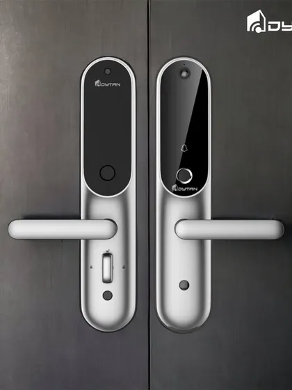 A sleek silver smart lock that blends seamlessly with modern doors. It features a discreet camera and bell icon, integrating multiple functions into one device.