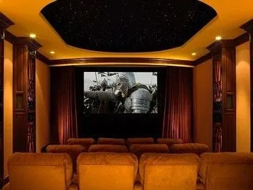A traditional home theater featuring warm wood columns, tiered fabric seating, and a recessed starlight ceiling. The design balances classic architectural elements with modern home cinema technology for a sophisticated result.