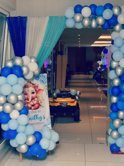 This entrance arch for a first birthday features a cute baby Ganesha welcome board. The blue and silver balloon arch creates a festive and auspicious entryway for the celebration.