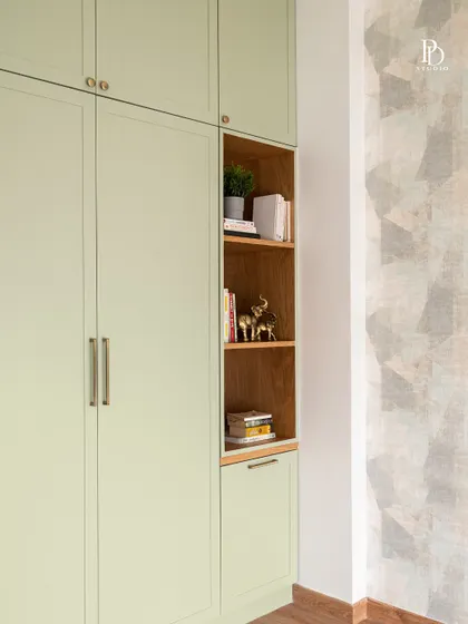 This sage green wardrobe includes a built-in open bookshelf, providing a beautiful and practical space for displaying books and personal treasures. It adds a touch of warmth and breaks the monotony of solid doors.