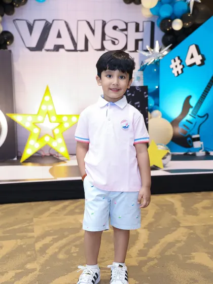 The birthday boy, Vansh, standing proud in front of his rockstar-themed stage. The backdrop features his name in bold letters, a giant light-up star, and cool graphic elements for his 4th birthday bash.