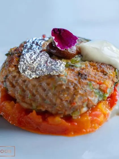 A close-up of the Mutton Gilafi, showcasing the delicate garnish and the glistening edible silver leaf. This is a dish that delights the eyes as much as the palate.