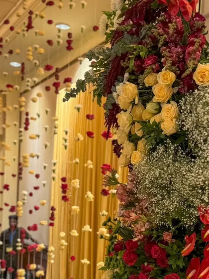 A close-up of the lush floral pillars of a traditional mandap, showing the rich combination of red and yellow roses with baby's breath.