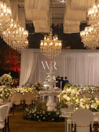 For this destination wedding reception, we created a dreamscape with over forty chandeliers casting a glow over an all-white setting. The combination of draped ivory canopies, a central water fountain, and lush white rose arrangements delivered the "whispered grandeur" this couple dreamed of.
