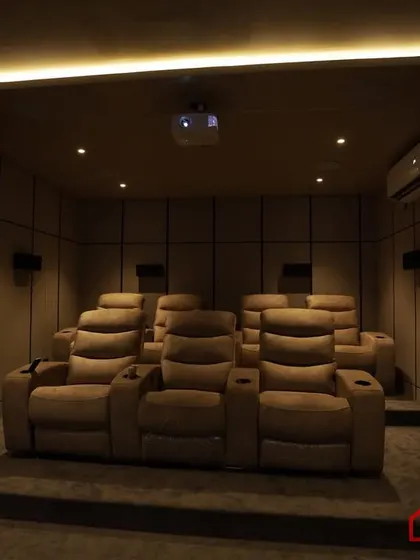 The tiered seating arrangement with plush, beige recliners, illuminated by soft, indirect cove lighting.