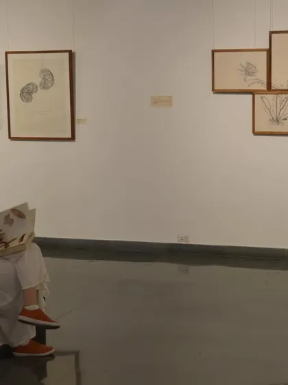 A visitor sits and reads through one of the artist's books at 'Bring me Flowers', demonstrating the quiet, interactive nature of the show.