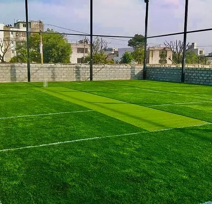 A wide view of a community sports ground featuring a cricket pitch. The surrounding stone wall and netting were part of the complete turnkey solution I provided.