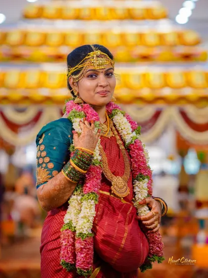 A beautiful portrait of a South Indian bride in her vibrant red and green wedding saree, adorned with traditional jewelry and garlands.