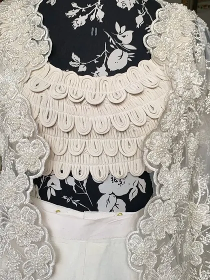 A close-up of the scalloped, textured blouse and the hand-embroidered jacket. This outfit is a true head-turner.