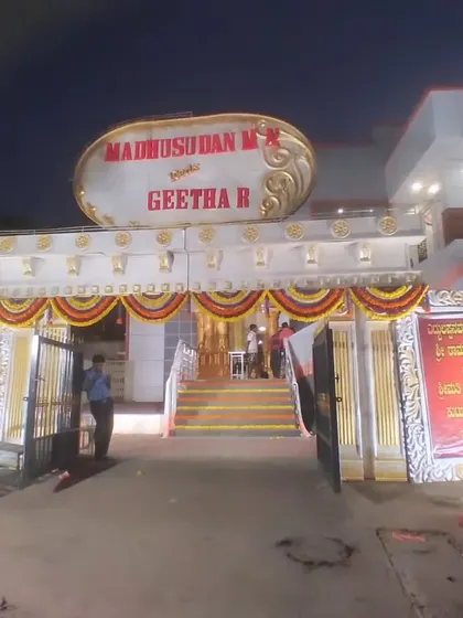 A large, ornate welcome structure at the entrance of a venue, featuring the couple's names and traditional decorative elements.