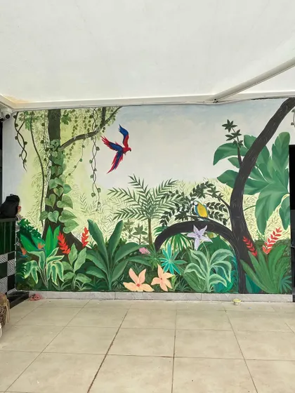 We call this our tropical paradise. We transformed the walls of a restaurant with a misty forest theme, covering even the doors to create a seamless, immersive jungle experience with colorful birds and lush greenery.