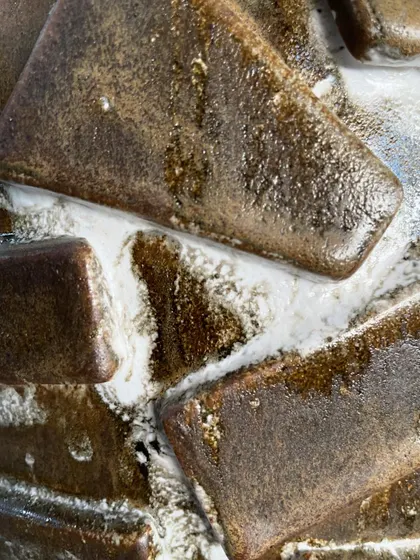 An extreme close-up of two different glazes interacting on a test piece. The way the brown and white glazes melt and push against each other creates a fascinating, organic pattern.