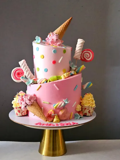 The pink topsy-turvy candyland cake presented on a gold stand, showing its full whimsical design.