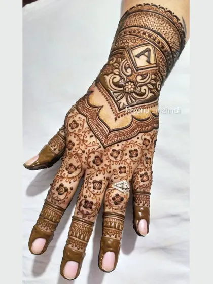 A similar design style with the initial 'A' at the wrist. The intricate floral pattern on the palm is consistent, showing how this style can be personalized for any client.