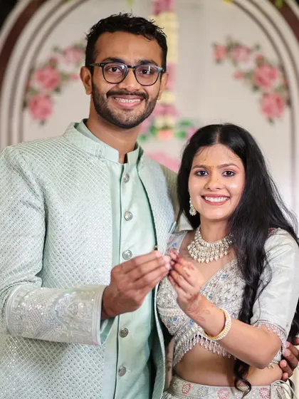 A classic portrait of a smiling engaged couple proudly displaying their rings.