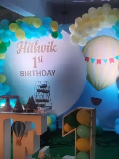 A "Hot Air Balloon" adventure theme for Hithvik's first birthday. The design features a custom circular backdrop, large "ONE" props with hot air balloon details, and blue, yellow, and green balloons.