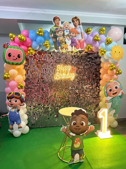 A full view of the Cocomelon party decor, showing the balloon columns and the large light-up number '1'.