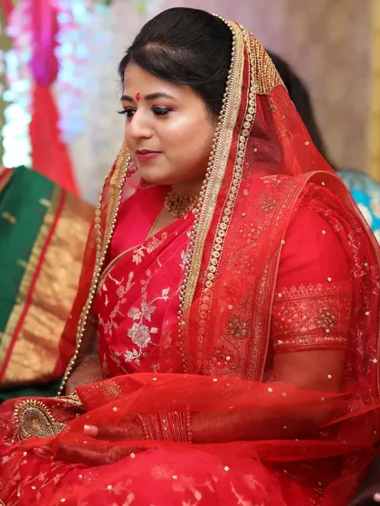 Here is the bride during her engagement ceremony, with a delicate veil. The makeup features soft, shimmery eyes and a natural base, creating a look that is both traditional and gracefully understated.