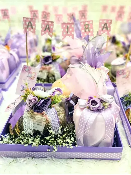 Announcing a baby girl with shades of mauve and pink. This tray is filled with individually wrapped gifts and personalized with the baby's name, creating a beautiful presentation.