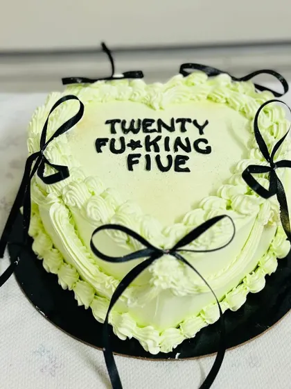 A trendy heart-shaped cake with black ribbons, perfect for a 25th birthday.