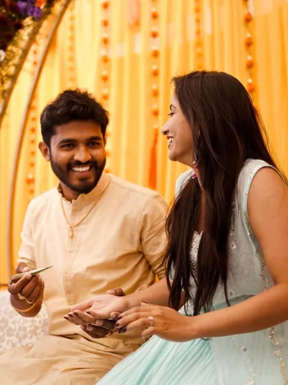 A candid moment of laughter during a Mehendi function. The background shows our bright yellow drapes and floral decor that set a festive mood.
