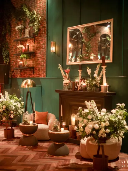 A cozy corner by a fireplace in the glass house reception. The combination of emerald green walls, exposed brick, and soft lighting created a space that felt like a stylish, vintage home.