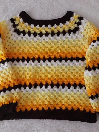 A flat-lay of the Trinity Sweater, showcasing the top-down construction and vibrant color pattern.