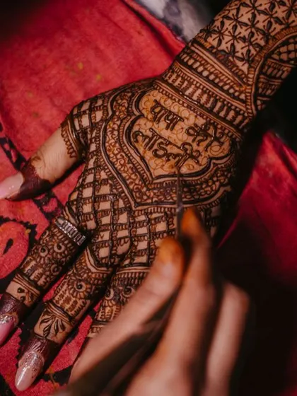 A close up shot of me carefully writing 'Papa ki Laadli' (Daddy's girl) within the intricate bridal henna. These personalized phrases make each design a unique expression of love and family.