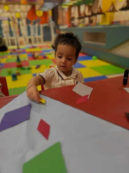 A toddler works independently on her craft, a sign of growing confidence and focus.
