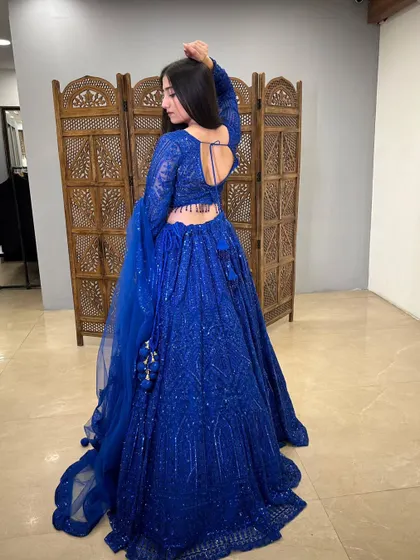 A back view showcasing the open-back design and the full, flowing skirt of the blue lehenga.