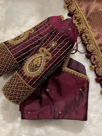 A still shot of the wine-colored bridal blouse, showcasing the incredible detail on the sleeves and the delicate tassels on the saree border.