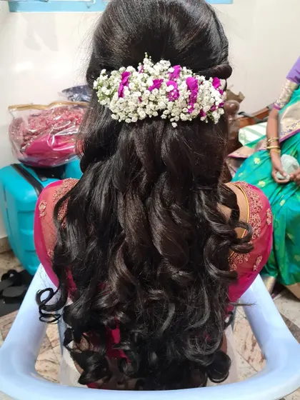 A beautiful half-up, half-down hairstyle with soft waves. Fresh baby's breath and purple flowers are woven in for a romantic and elegant touch.