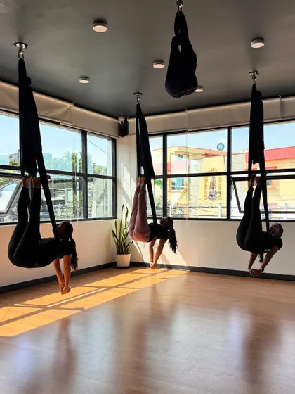 Students hold a suspended core-strengthening pose, building stability and endurance.