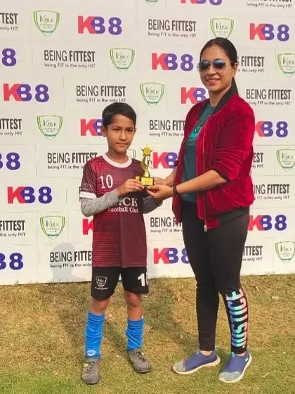 A Kick FC player receives his "Player of the Match" trophy for his standout performance.