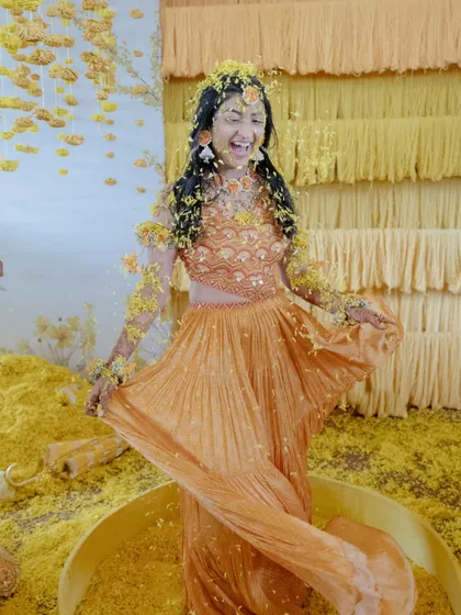 The bride's joyous moment during her 'Phoolon Ki Holi' Haldi in Kochi, showered with flower petals.