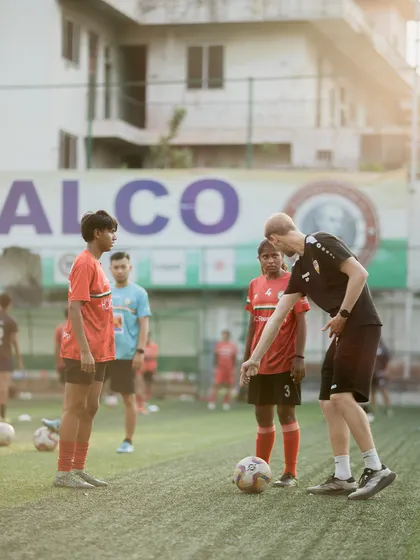 A VfB Stuttgart coach corrects a player's stance, focusing on the small details that make a big difference. This meticulous approach to coaching is what sets our training apart.