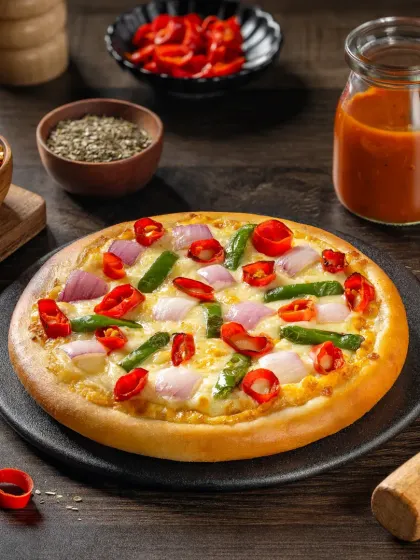 A spicy vegetable pizza with red chilies, onions, and capsicum, styled with fresh ingredients to highlight its heat.