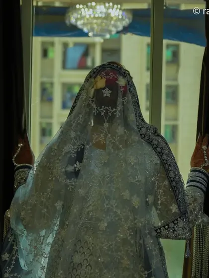 An artistic silhouette of the bride standing against a window, her form veiled and mysterious. This creative shot adds drama and variety to a wedding gallery.