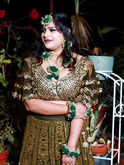 A candid portrait of the bride, looking elegant and happy. The focus is on her beautiful floral jewelry and the joy of the occasion.