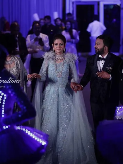 A candid moment during the couple's sangeet entry. The joy on their faces is amplified by the spectacular visual display of the LED dancers surrounding them.