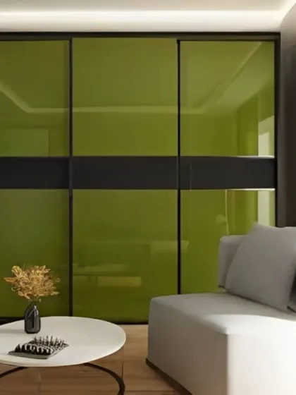 A sleek sliding wardrobe with olive green lacquered glass panels. The black metal frame adds a modern, industrial touch, and the reflective surface helps make the room feel larger.
