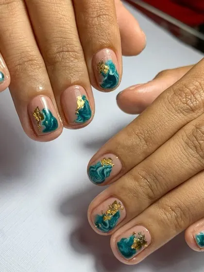 A beautiful marble or "blooming" gel effect on natural nails, accented with flecks of gold foil.