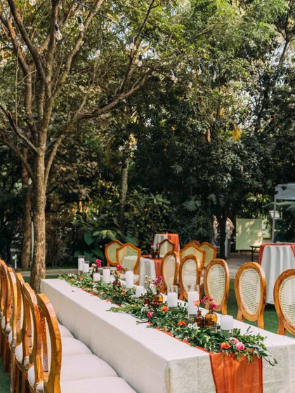 An elegant long-table dining setup for an intimate wedding cocktail party. The floral runner and candles create a warm and inviting atmosphere for guests.