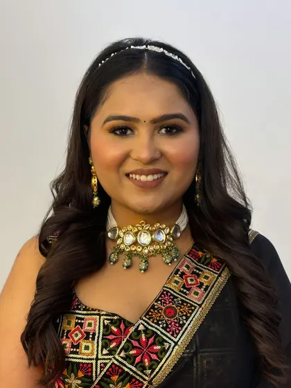 A smiling portrait of the client, showing how the makeup brightens her face and complements her traditional yet modern outfit.