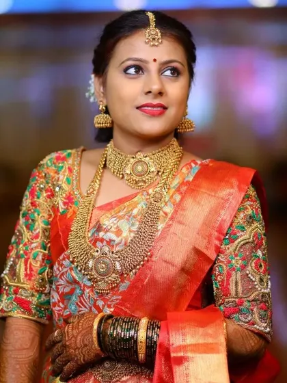 A beautiful portrait of a bride in her reception attire. Her multi-colored printed silk saree is elevated by a custom blouse with dense, matching floral and vine pattern embroidery.