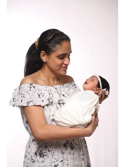 A mother gazes lovingly at her sleeping newborn cradled in her arms. This candid-style portrait captures the deep affection and connection in a natural, beautiful way.