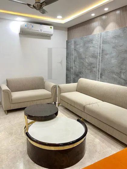 Another angle of this living room, showing the pairing of the two-seater and three-seater sofas. The nested coffee tables with their contrasting tops serve as a central focal point.