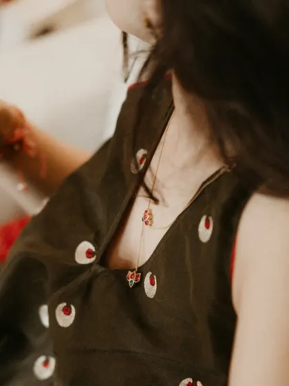 A close-up of the bride's delicate necklace and the unique embroidery on her homegrown label outfit.